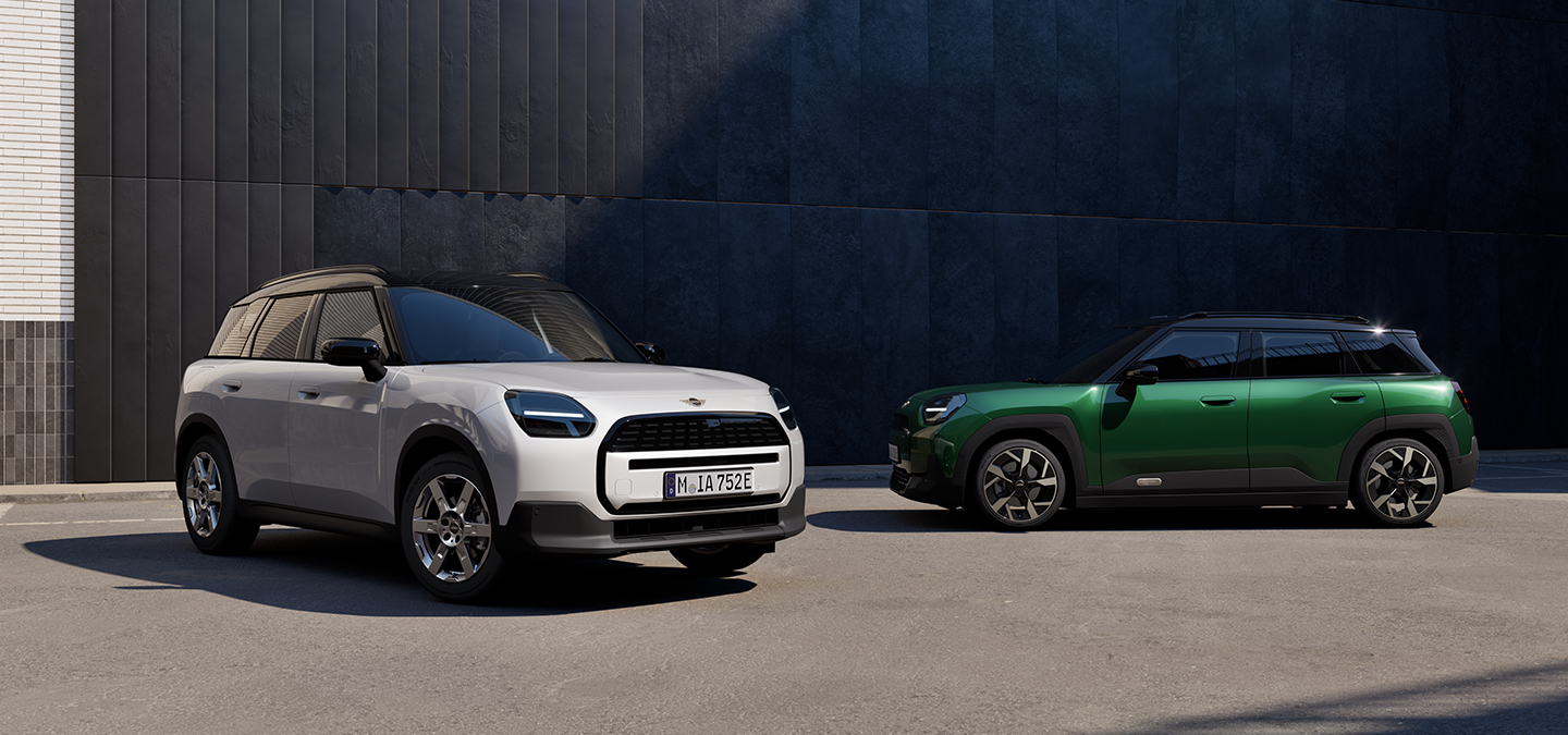 Front and Side view of the all-electric MINI Aceman in Nanuq White and British Racing Green with Black roof on a street.