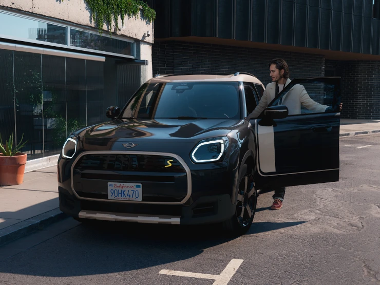 Front view of the all-electric MINI Countryman in Midnight Black and Vibrant Silver Roof on a street.