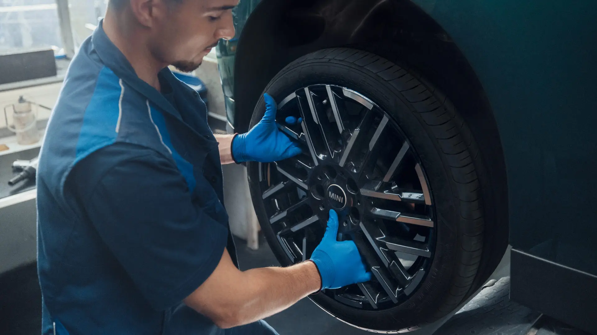 A MINI service technician installs a MINI 18" Night Flash Spoke Bicolour Light Alloy Wheel onto a MINI Cooper Electric.